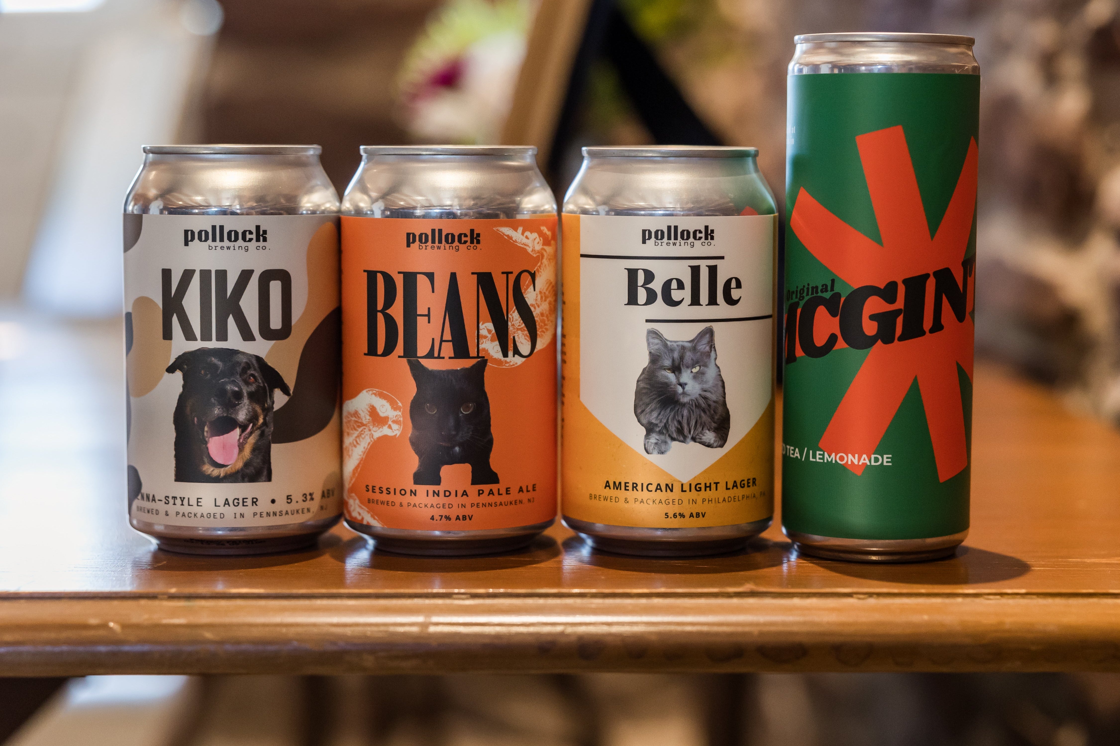 Four beer cans with different designs and text on a wooden table.